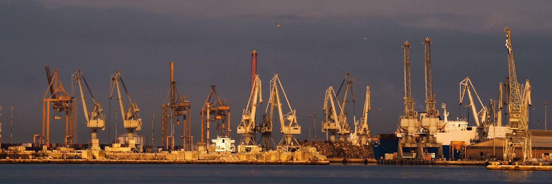 Kräne eines griechischen Frachthafens in der Abenddämmerung
